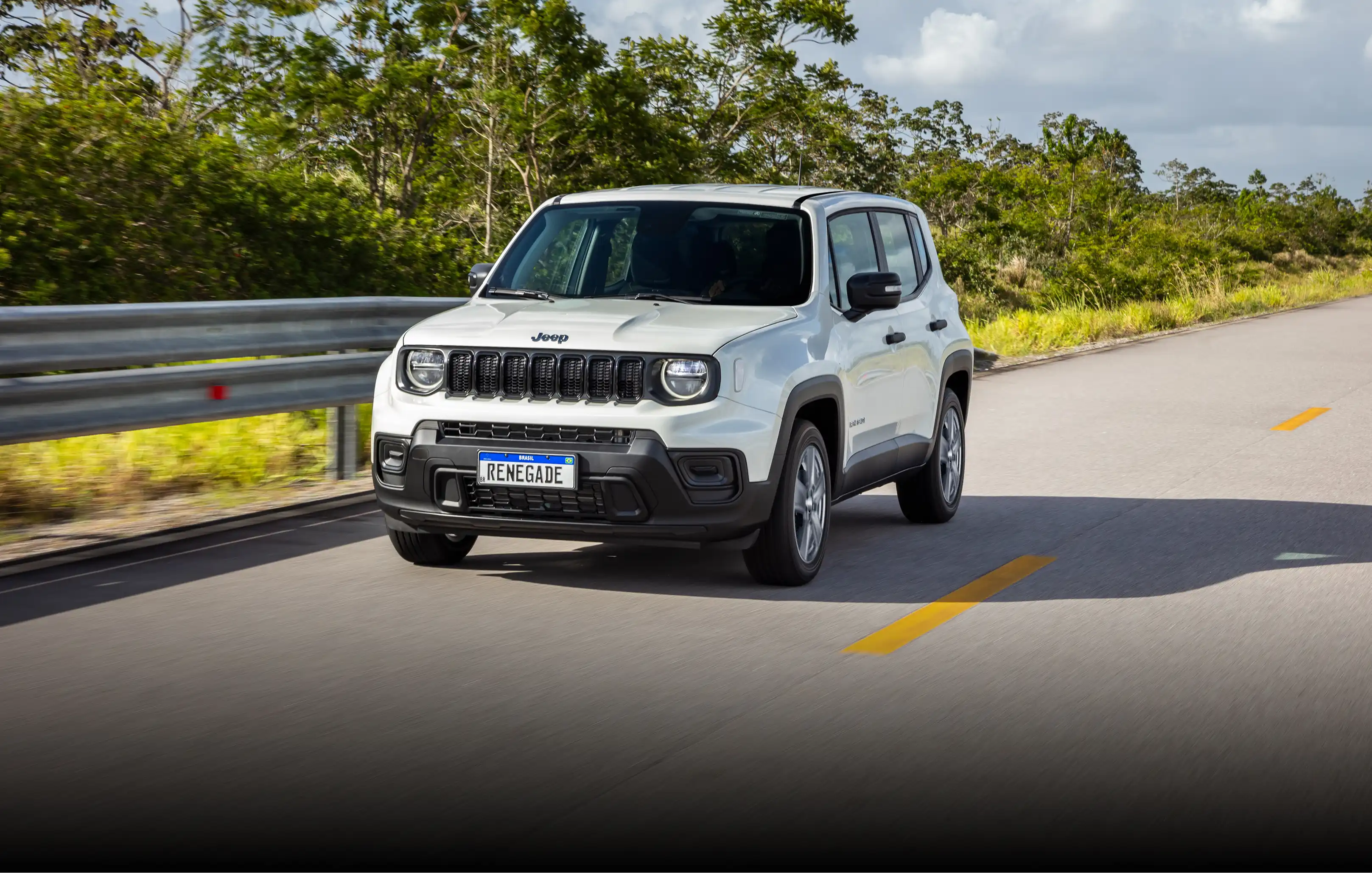 Vista frontal de Jeep Renegade na cor branca em estrada com vegetação baixa e média na lateral