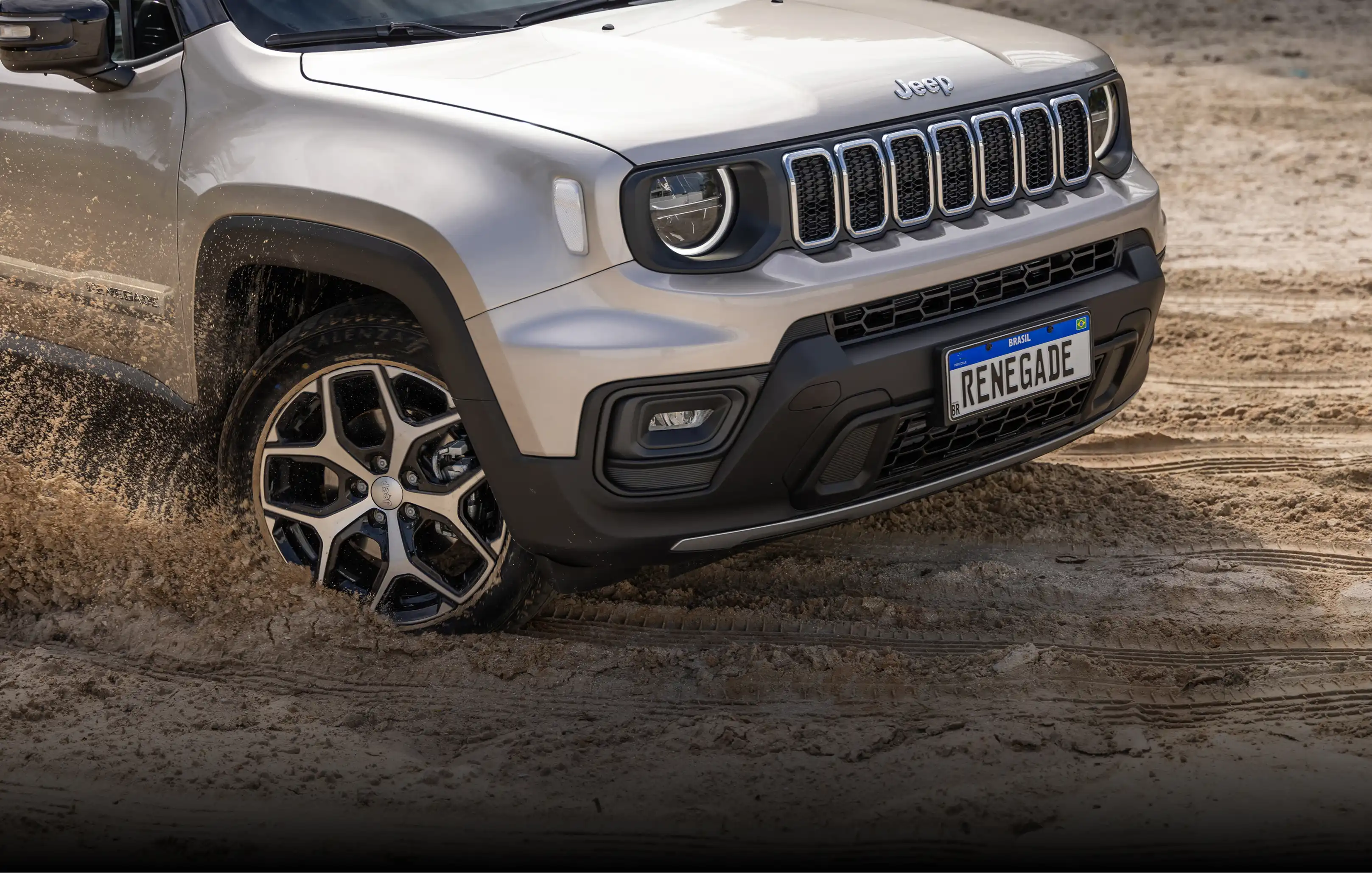 Vista dianteira e lateral de Jeep Renegade na cor prata em terreno arenoso