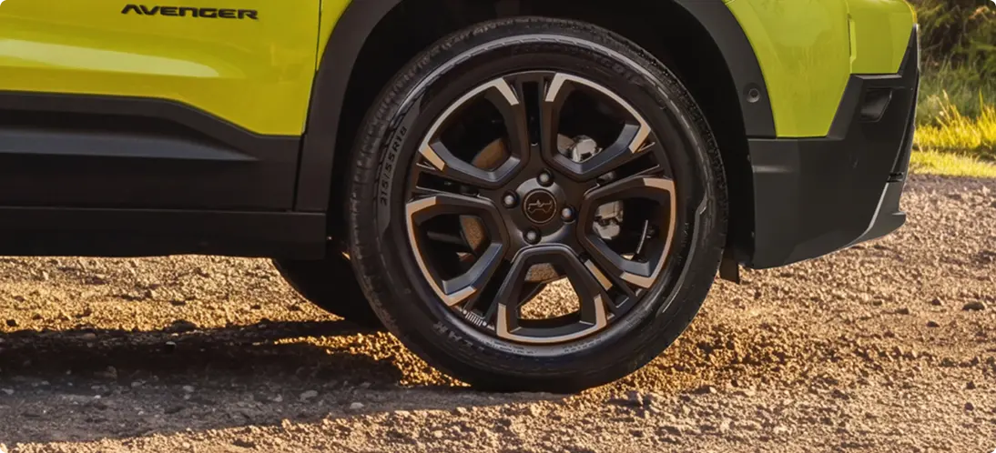 Rodas de Liga-leve Jeep Avenger verde com detalhe da roda de liga leve escurecida, pneu e para-lama dianteiro visíveis.