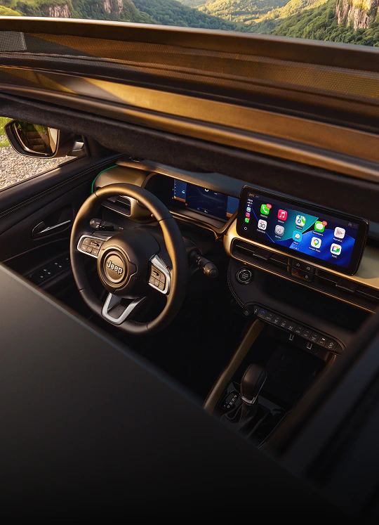 Interior do Jeep Avenger com volante multifuncional, painel digital e central multimídia exibindo ícones de aplicativos.